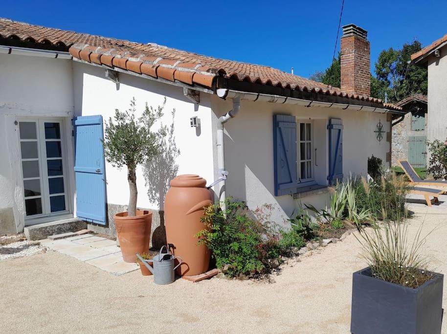 une petite maison blanche avec des portes bleues et une cour dans l'établissement La Petite Grange, à Esse