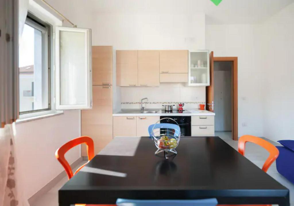 a kitchen with a black table and orange chairs at Casa Vacanze Nonna Rosaria al centro di Ascea Marina in Ascea