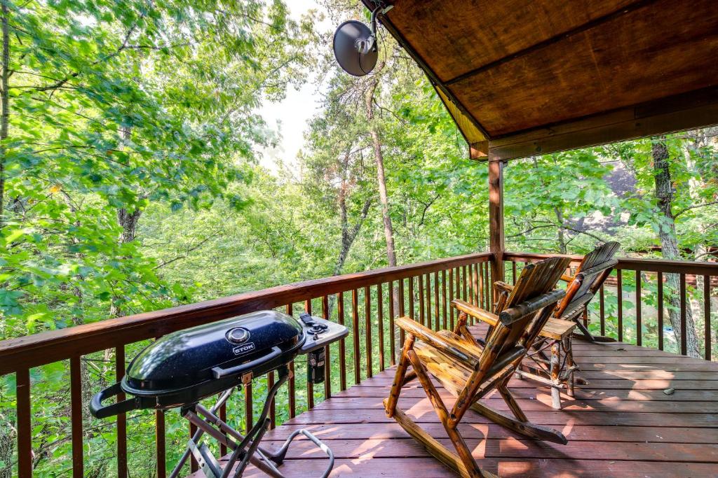 einen Grill und zwei Stühle auf einer Holzveranda in der Unterkunft Tennessee Cabin with Balcony, Hot Tub and Pool Access! in Sevierville