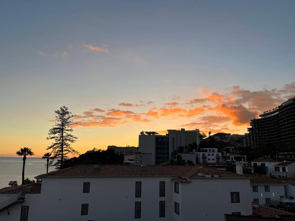 einen Sonnenuntergang über einer Stadt mit Gebäuden und dem Meer in der Unterkunft Marias sea cottage in Funchal