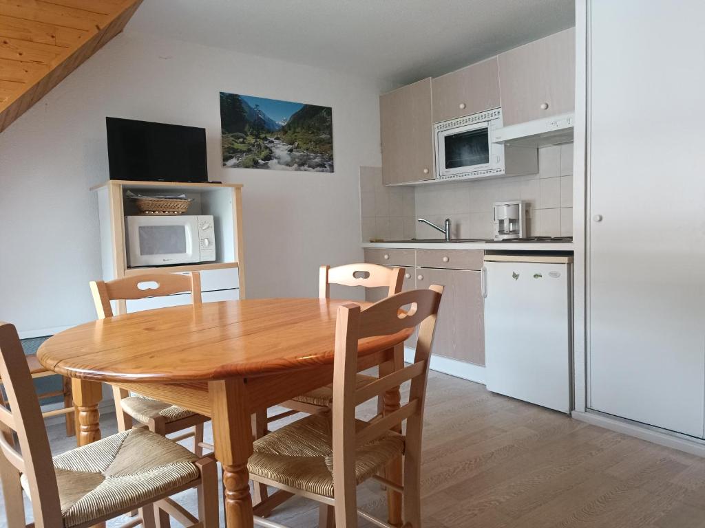a kitchen and dining room with a wooden table and chairs at Joli T2 avec alcôve Wifi 4 pers linge de maison inclus in Cauterets