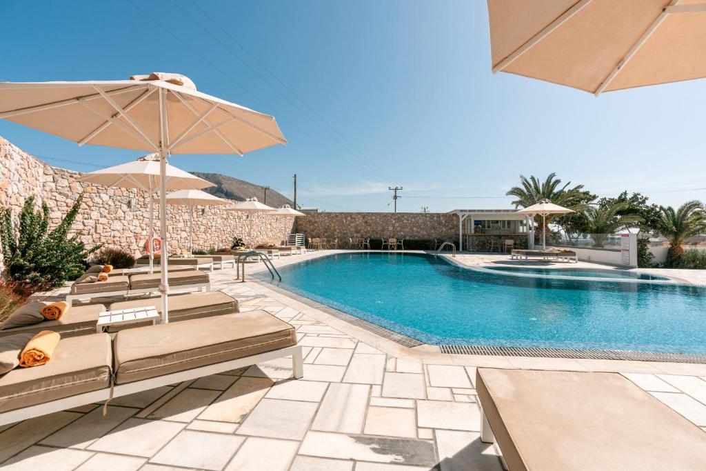 a swimming pool with benches and an umbrella at Margarenia in Perissa