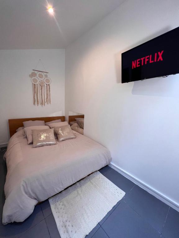 a bed in a room with a sign on the wall at Studio proche Stade de France in Saint-Denis