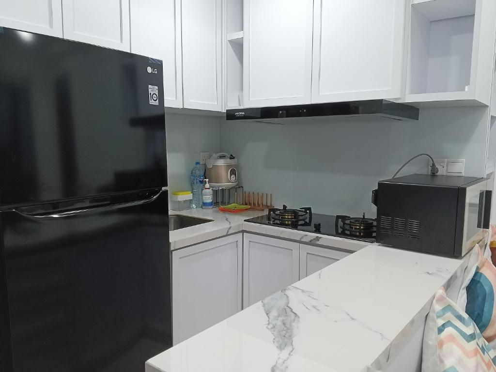 a kitchen with white cabinets and a black refrigerator at Peaceful Sea view Cozy APT at Batam Center - By MESA in Batam Center