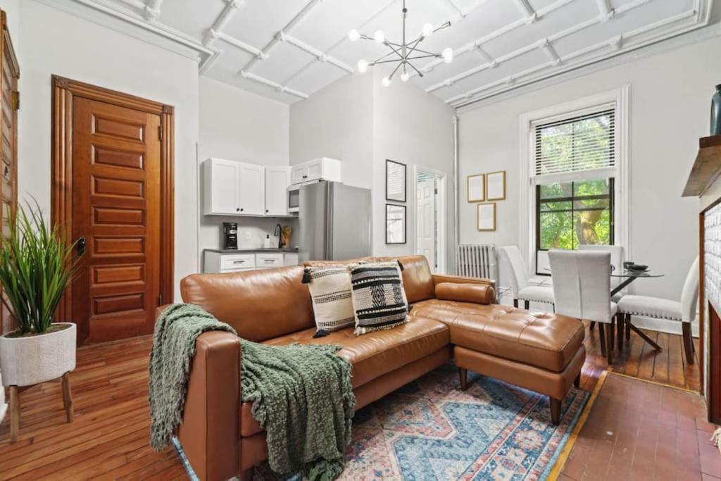 a living room with a brown leather couch and a kitchen at Newly Renovated 2BR Haven Walk to Columbia Uni in New York