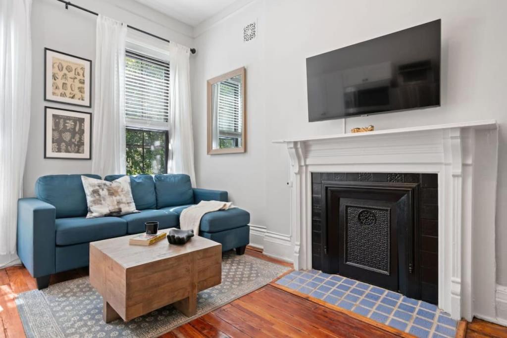a living room with a blue couch and a fireplace at Newly Renovated 3BR Oasis Walk to Columbia Uni in New York