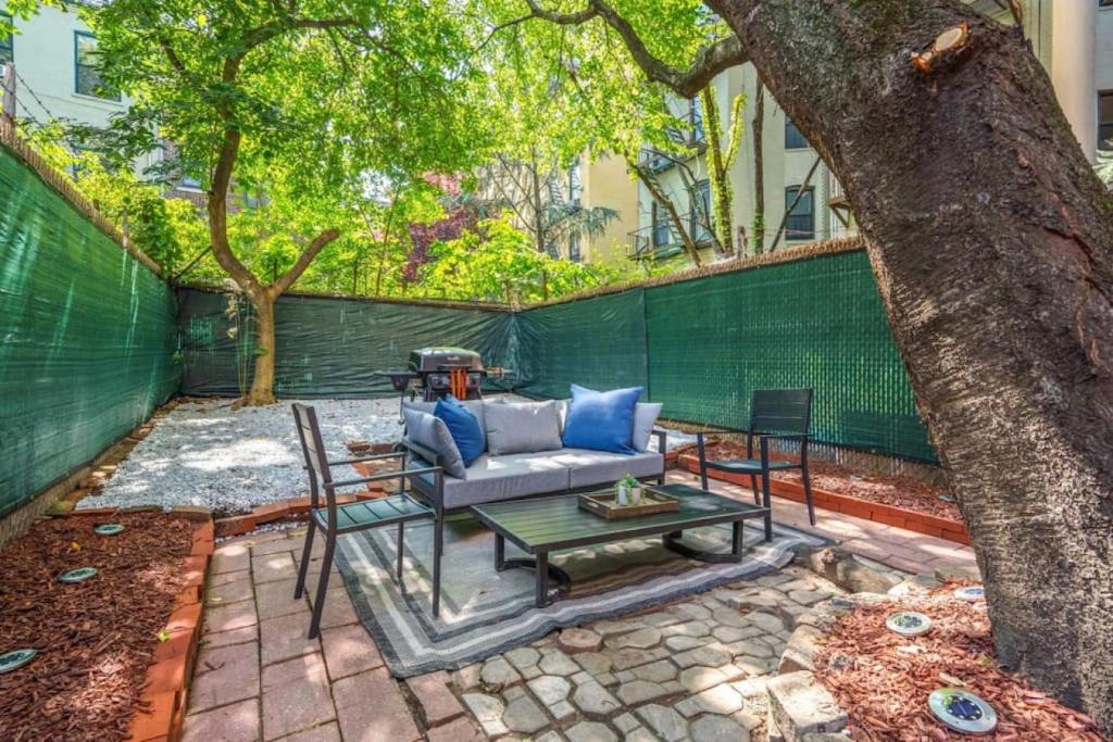 a patio with a couch and a table under a tree at Newly Renovated 2BR w Rare Private Backyard and BBQ in New York