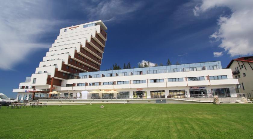 un grande edificio con un campo verde davanti di Apartman 106 Panorama Resort Štrbské Pleso a Štrbské Pleso