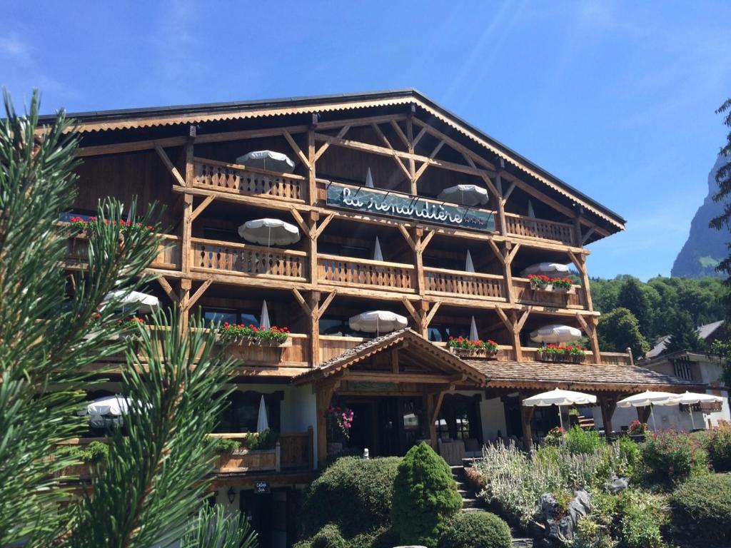 - un grand bâtiment en bois avec un balcon doté de parasols dans l'établissement Residence Hôtelière La Renardiere, à Samoëns