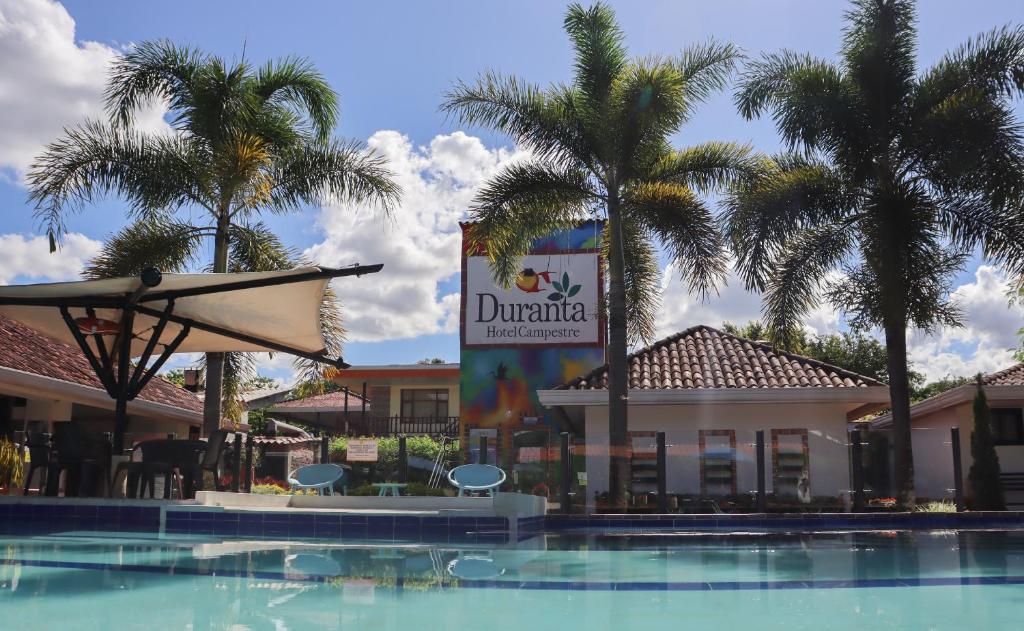 un cartel frente a un hotel con palmeras en Hotel Boutique Duranta, en Villavicencio