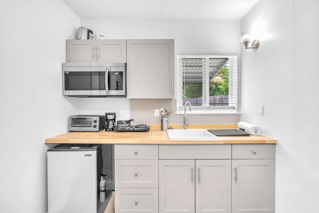 a white kitchen with a sink and a microwave at Blue Wave Bungalow - 1 1 - Stylish in Dania Beach