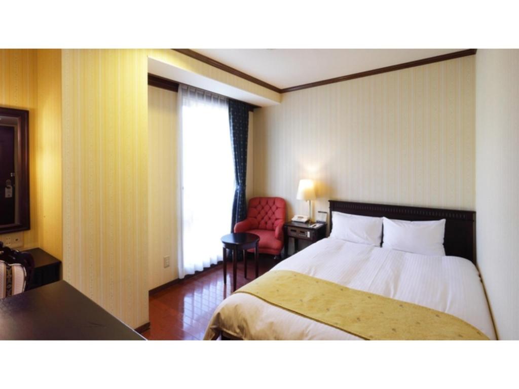 a hotel room with a bed and a red chair at Old England Dogo Yamanote Hotel - Vacation STAY 75541v in Matsuyama
