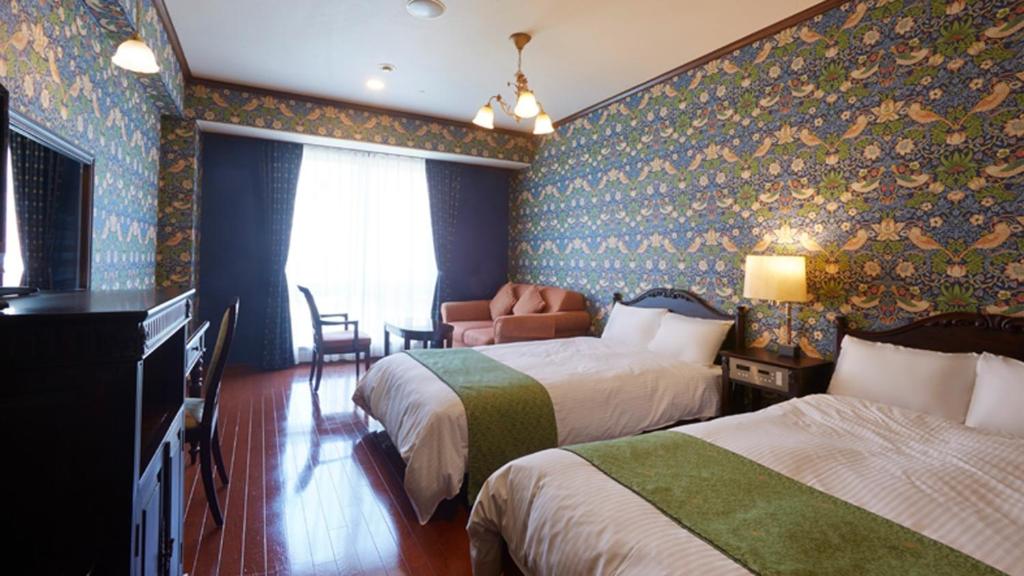 um quarto de hotel com duas camas e uma cadeira em Old England Dogo Yamanote Hotel - Vacation STAY 76375v em Matsuyama