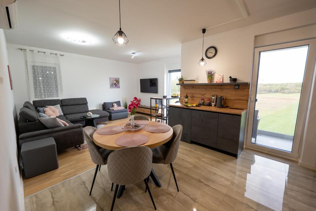 a kitchen and a living room with a table and chairs at Apartman Nebo - Pogled na Stari Grad i Minizoo besplatne ulaznice - Free tickets in Ðurđevac