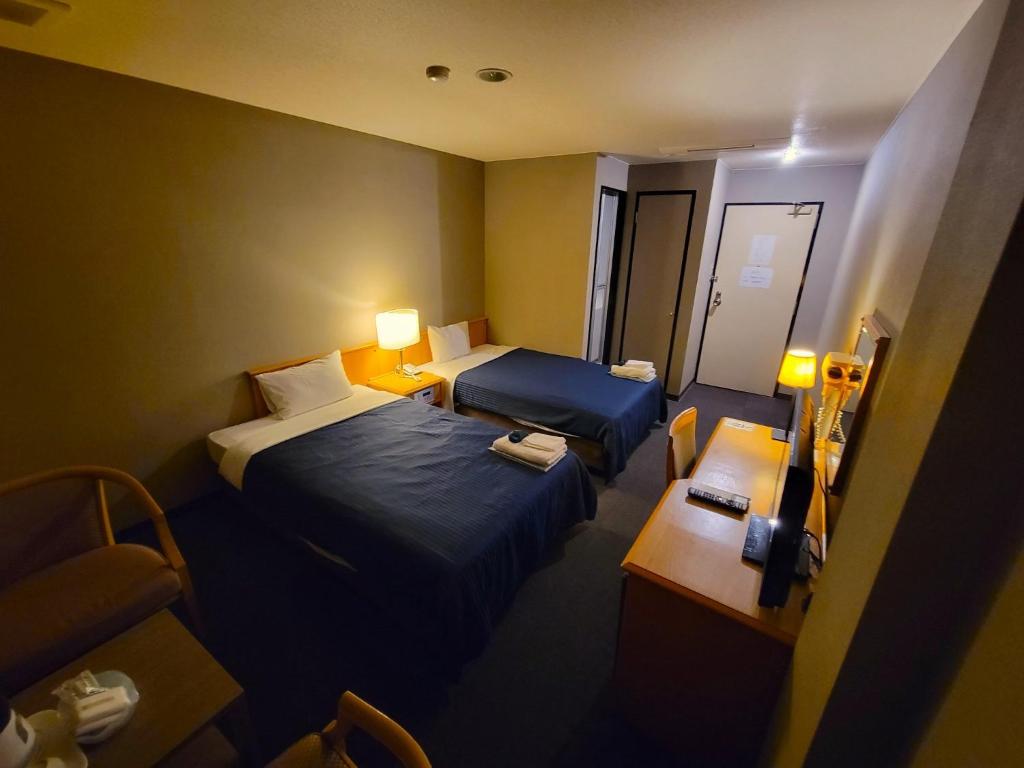 泉佐野市にあるHOTEL SEAGULL - Vacation STAY 86796vのベッド2台と椅子が備わる小さなホテルルームです。
