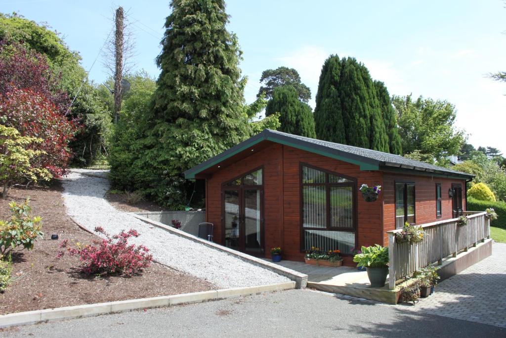 a small building in a garden with trees at Beechtree Chalet in Warrenpoint