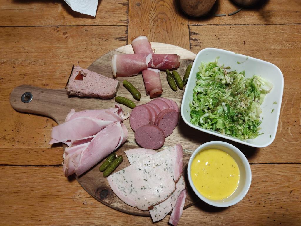 a cutting board with meat and vegetables and a bowl of dip at Au pied de la colline in Alembon