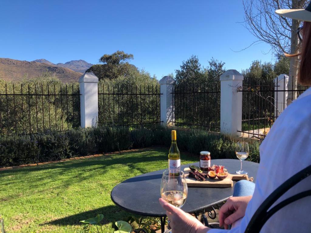 a person holding a glass of wine on a table at Gooding's Olive Villa in Franschhoek