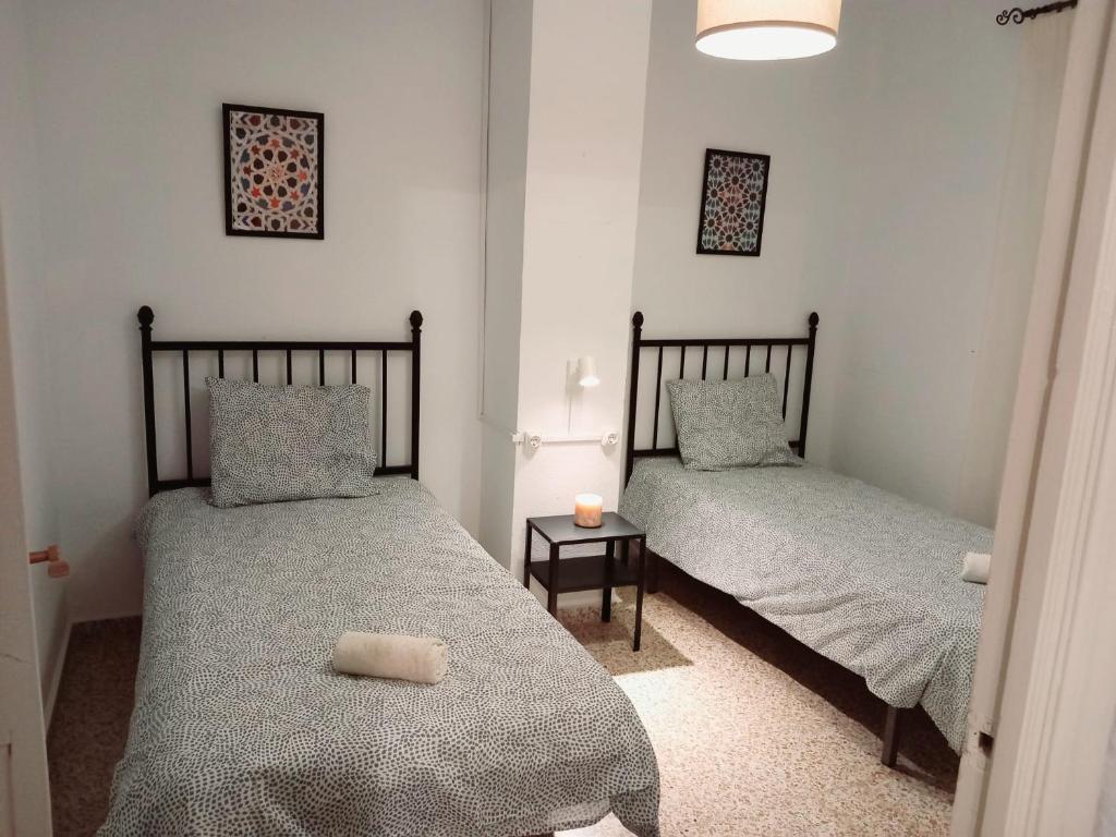 2 camas individuales en una habitación con mesa en Casa Abuela Antonia, en Granada