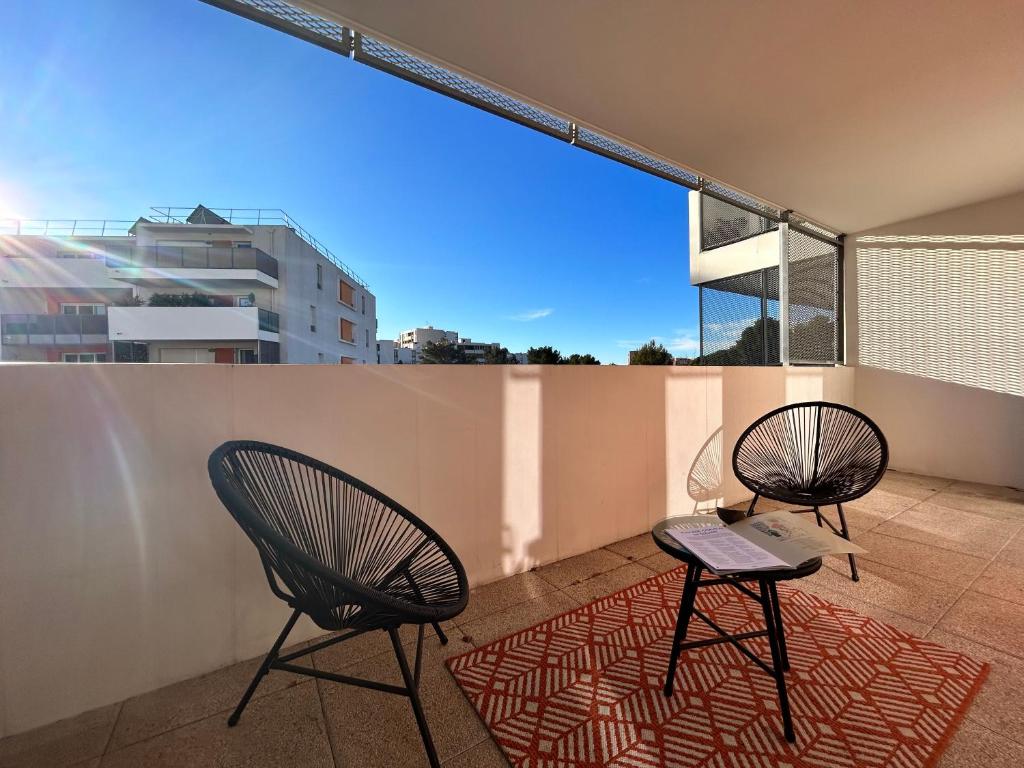 deux chaises et une table sur un balcon dans l'établissement « Terrasse Monticelli » by les Clefs de Charlotte, à Vitrolles