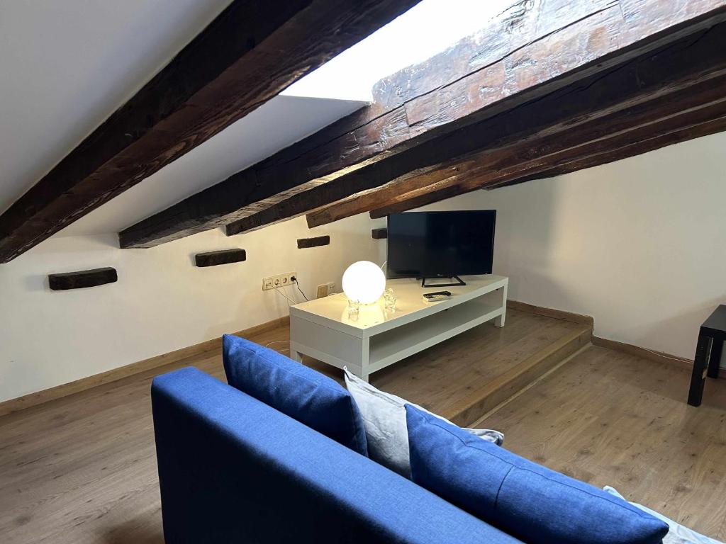sala de estar con sofá azul y TV en Cómodo Ático en Tirso de molina Madrid, en Madrid