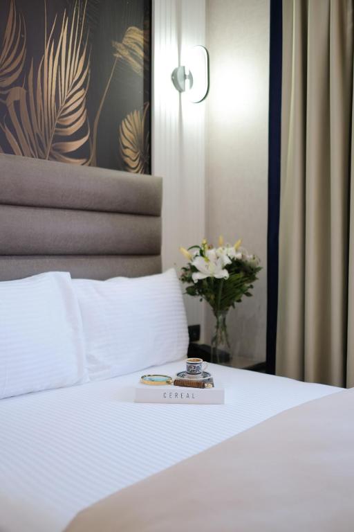 a white bed with a clock on top of it at Dem Premium Hotel - Round Trip Airport Service - Istanbul International Airport in Arnavutköy