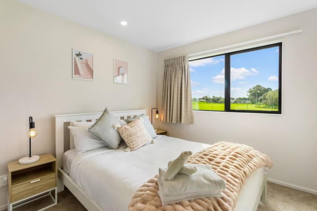 a bedroom with a bed and a large window at Urban Glow Townhouse with parking in Auckland
