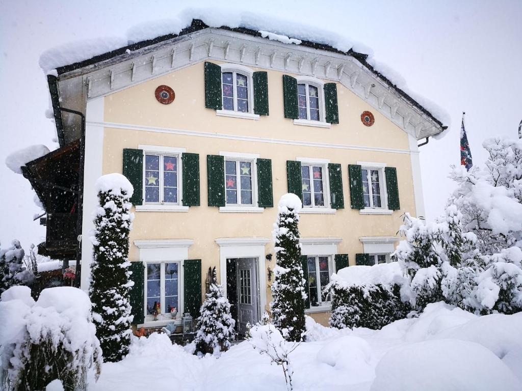 dom z zielonymi okiennicami w śniegu w obiekcie Ferienwohnung Waltensburg w mieście Waltensburg