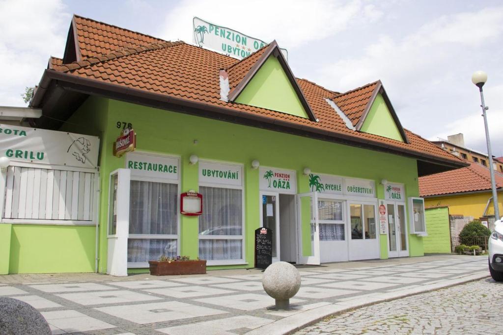 a green building with a red roof at Penzion Oaza in Luhačovice
