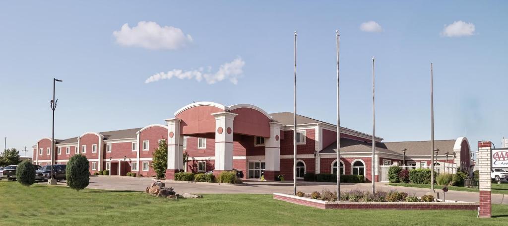 a large red brick building in a parking lot at Invision Inn - Dumas in Dumas