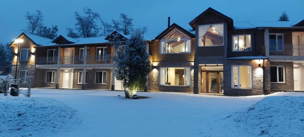 a large house with snow in front of it at Hostería Las Semillas in Villa La Angostura