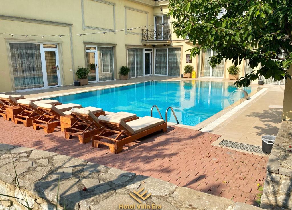a large swimming pool with lounge chairs and a hotel at Hotel ERA in Pristina