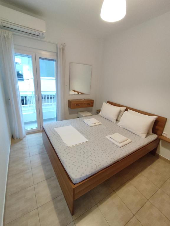 a bedroom with a bed with two tables and a window at Sea View Apartments Nikos in Nea Peramos