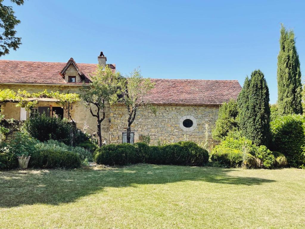 an old stone house with trees and a yard at 1700's Country House with large Private Pool & Gardens in Villeneuve-dʼAveyron