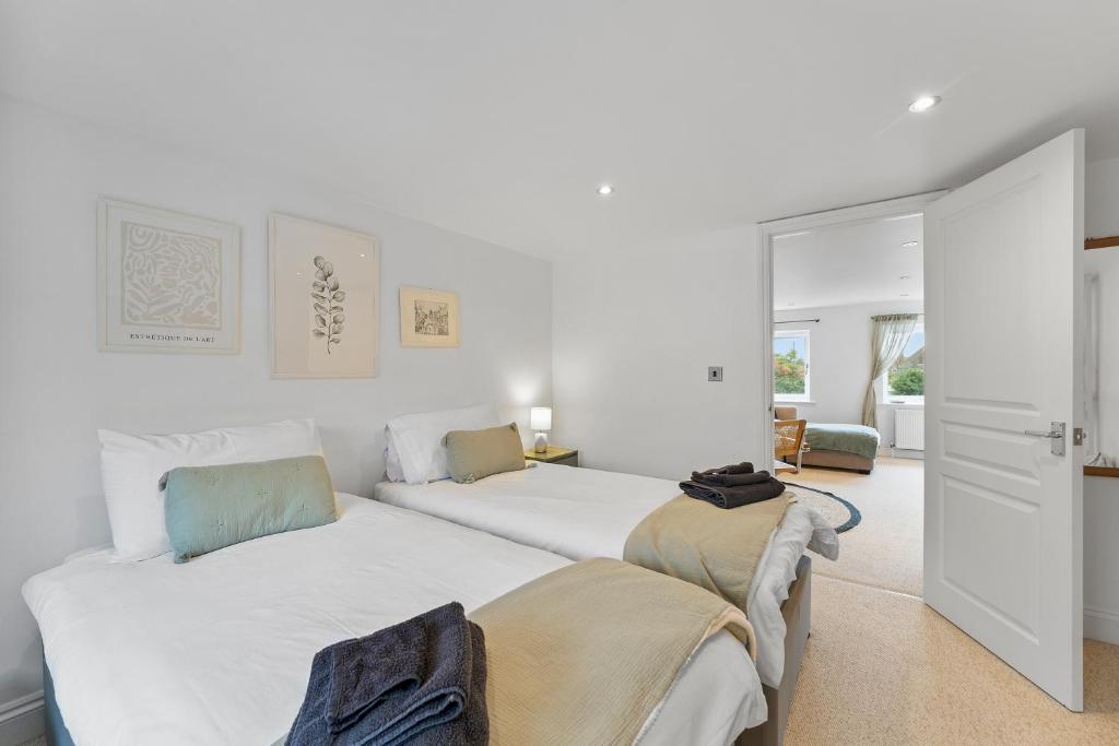 two beds in a room with white walls at Sea la Vie! Beautifully furnished home in Central Whitstable in Kent