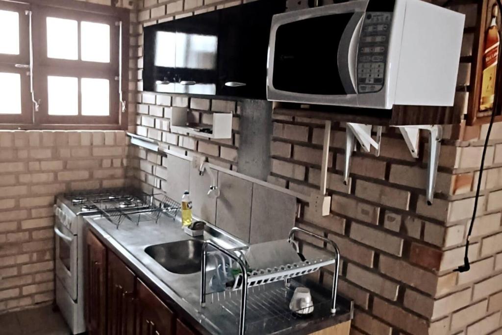 a kitchen with a sink and a microwave at Sobrado praia cachoeira in Florianópolis
