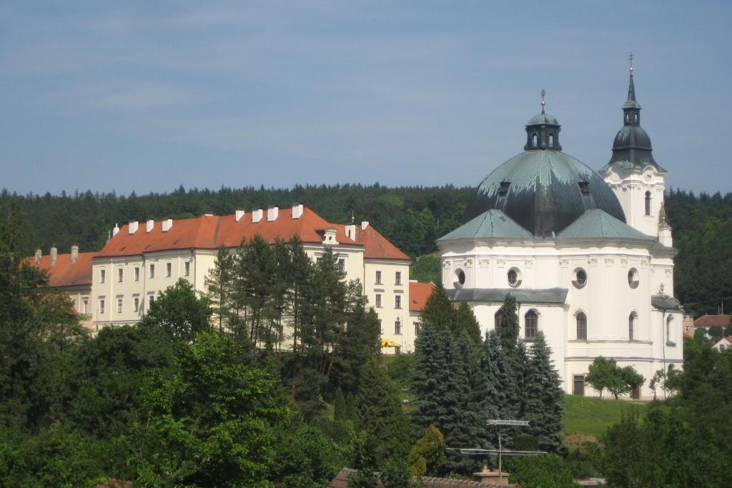 een groep gebouwen op een heuvel met bomen bij Zámek Křtiny in Křtiny