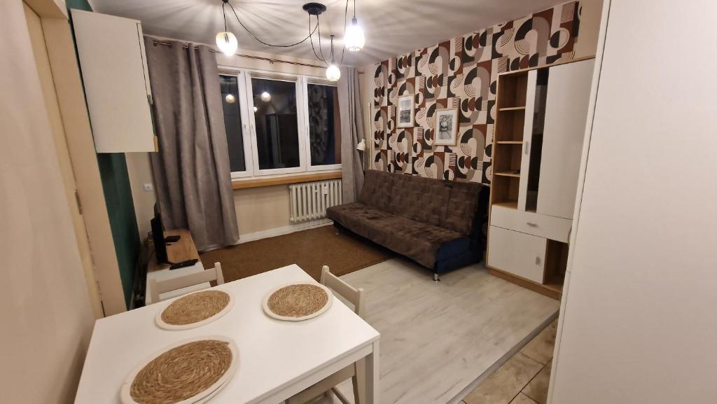 una pequeña sala de estar con mesa y sofá en Apartament Poselska en Legnica