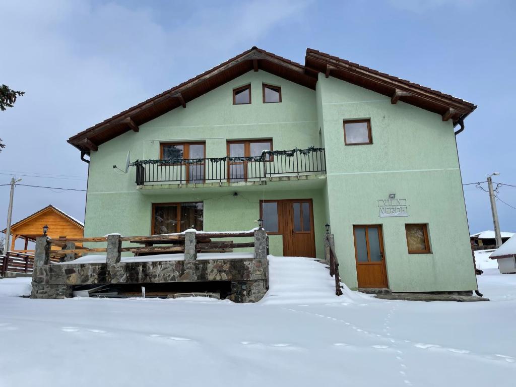 zielony dom z balkonem w śniegu w obiekcie Vila Verde Păltiniș w mieście Poplaca