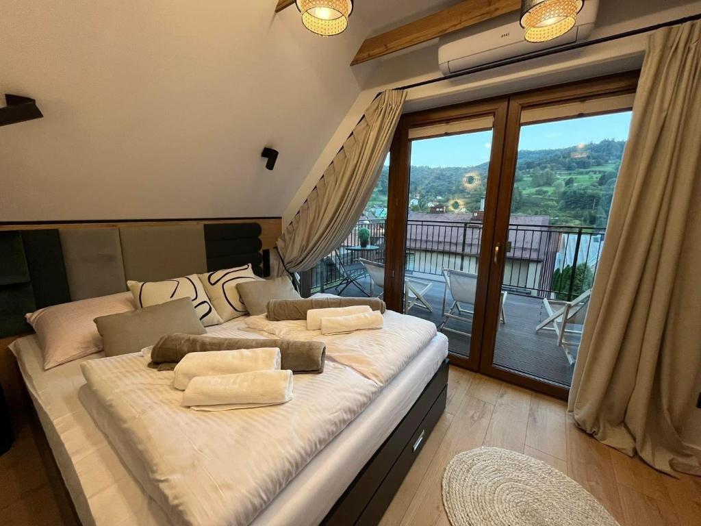 - duże łóżko w pokoju z balkonem w obiekcie Domki Pienińskie Tarasy w mieście Szczawnica