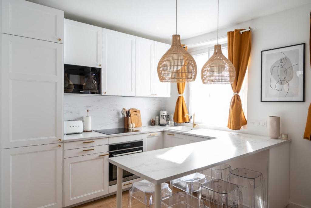 a kitchen with white cabinets and a white table at Beautiful duplex on the outskirts of Paris - Welkeys in Levallois-Perret