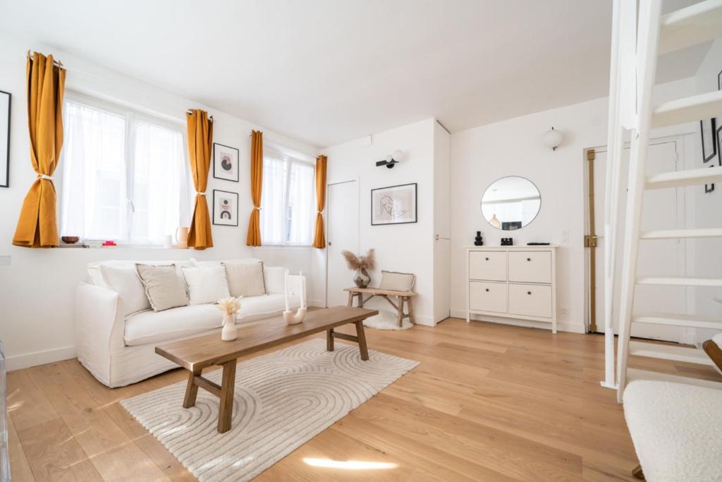 a living room with a white couch and a table at Beautiful duplex on the outskirts of Paris - Welkeys in Levallois-Perret