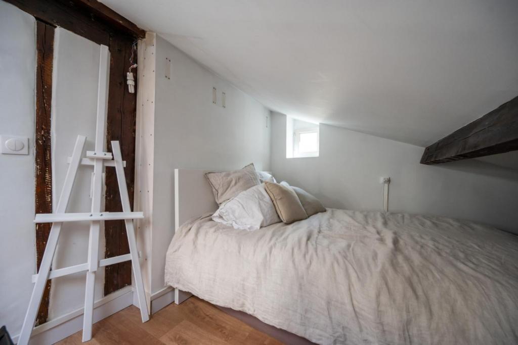 a white bedroom with a bed and a ladder at Beautiful duplex on the outskirts of Paris - Welkeys in Levallois-Perret