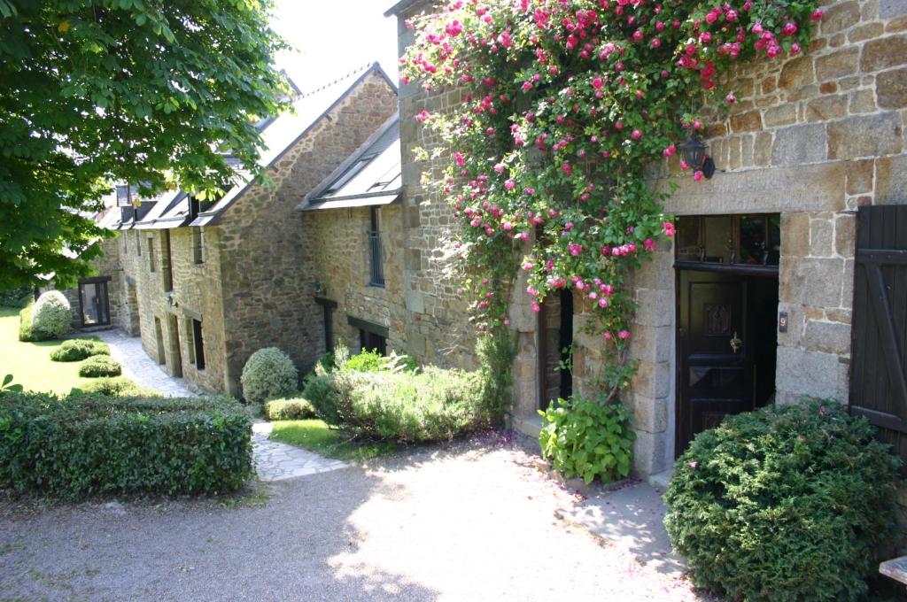 Un bâtiment avec un bouquet de fleurs roses sur lui dans l'établissement Ferme Saint Christophe, à Saint-Marcan