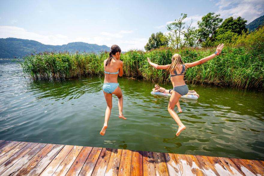 two women jumping into a body of water at Feriennest Ossiachersee in Bodensdorf