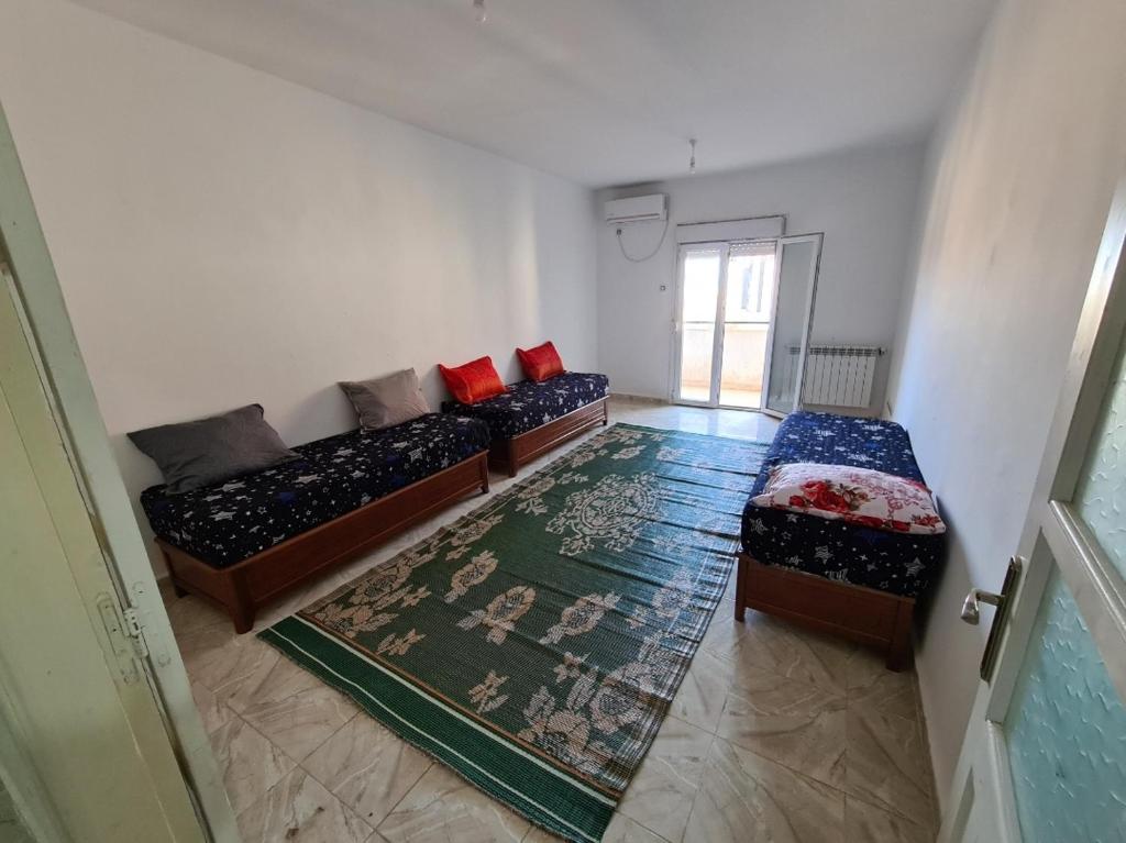 een kamer met 2 bedden, een bank en een tapijt bij Cité 200 logement mimouni borj el Kiffan alger in Fort de lʼEau