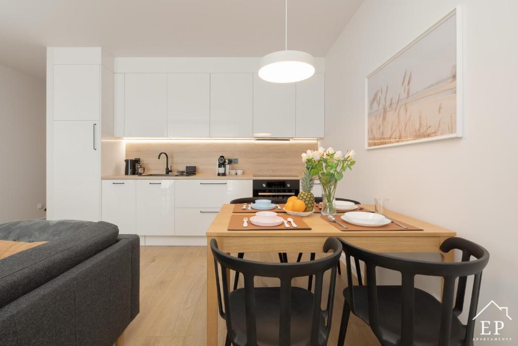 un salon avec une table et des chaises et une cuisine dans l'établissement Apartament MARE 13 Marina Dziwnów & SPA Basen EPapartamenty, à Dziwnów