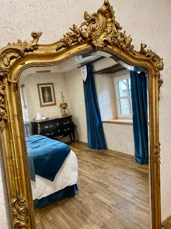 - un grand miroir en or dans une chambre avec un lit dans l'établissement Une nuit chez une artisane, à Josselin