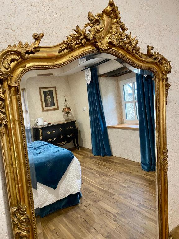 een grote gouden spiegel in een slaapkamer met een bed bij Atelier Corinne G : la chambre 9 in Josselin