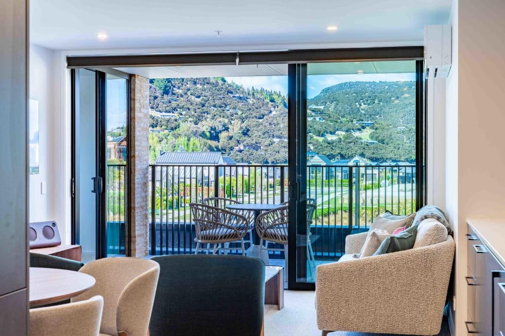 ein Wohnzimmer mit einem Balkon mit einem Tisch und Stühlen in der Unterkunft Majestic Mountain-View Retreat in Wanaka